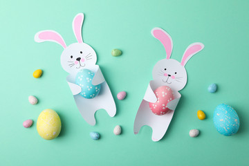 Decorative bunnies and Easter eggs on mint background, top view