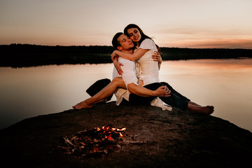Young couple embracing and kissing on Sunset coast near the fire. Romantic love story.