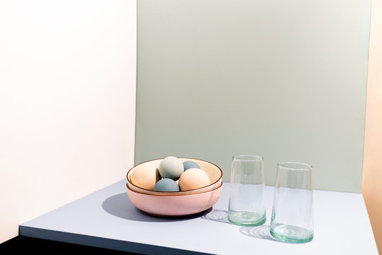 Still life image with stacked ceramic bowls, glasses, and colored balls