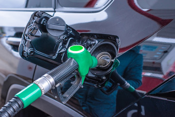 Closeup of woman pumping gasoline fuel in car at gas station. Petrol or gasoline being pumped into a motor vehicle car. Fueling tank of the car oil pump at bokeh background.