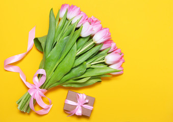 Pink tulips and craft gift box on yellow background.Flat lay,minimalism.Easter,spring flower concept,copy space.Mothers or Womans day.