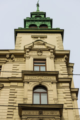 Nice white building and old green tower seen from below.