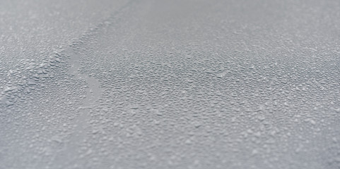 Raindrops on the hood of the car. Close-up.