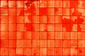 Red tile background. Old cracked paint on the wall. Uneven square blocks. Texture, pattern, background.