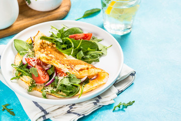 Omelette with green leaves at white plate.