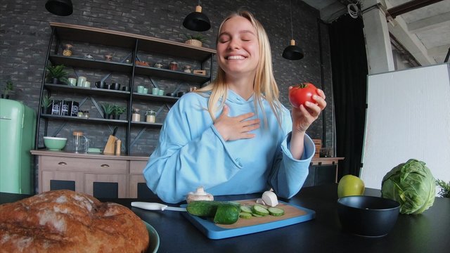 Young beautiful blonde takes on videos as she cooks in the kitchen