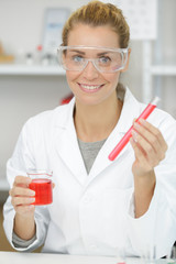 happy woman scientist adding liquid to test tube