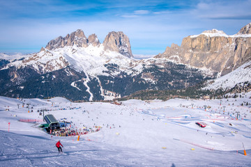 View of a ski resort piste with people skiing in Dolomites in Italy. Ski area Belvedere. Canazei,...