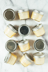 Homemade honey butter in glass jars on marble background