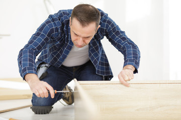 man using screwdriver to assemble furniture