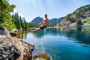 Fototapeta na wymiar Male hiker jumping into an alpine lake in Washington State.