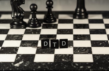 The acronym Dtd for Document Type Definition represented by black and white letter tiles on a marble chessboard with chess pieces