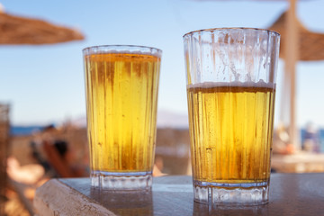 Two glasses of light beer on the sea beach