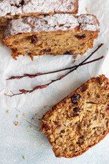 Spicy apple, nuts and dried cranberry loaf cake decorated with powdered sugar on a paper.