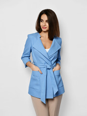 Young fashionable beautiful curly hair girl blogger trying on an expensive designer stylish light blue office suit jacket