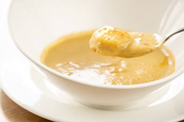 Fish soup in a white plate. Fish soup with vegetables, celery in a cup for the broth. Pike perch and salmon. Plate on wooden table. Restaurant menu