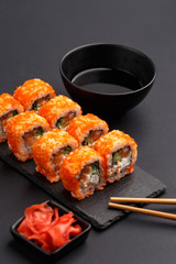 Sushi rolls on colored plates on a black background. A look from above.