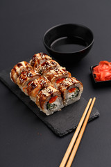 Sushi rolls on colored plates on a black background. A look from above.