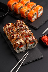 Sushi rolls on colored plates on a black background. A look from above.