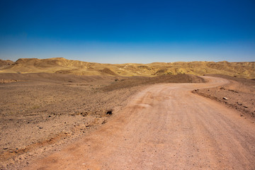 Israeli desert waste land global warming concept landscape scenic view of lonely dry ground trail ho horizon background space with sand stone mountain ridge and blue sky