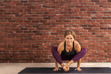 Sporty woman doing difficult pose, astavakrasana, asymmetrical arm balance eight Angle Pose. Lady...