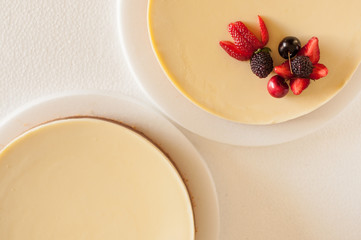 cake of three different chocolates with biscuit crunchy biscuit base and garnished with strawberry cherries and strawberries on a white plate