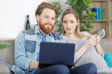couple drinking tea and using laptop in the apartment
