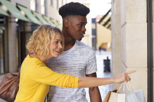 smiling couple looking at clothes in a shop window