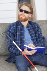 blind man reading braille book on the couch