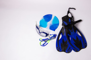 Pair of blue fins with swimming cap and goggles on a white background