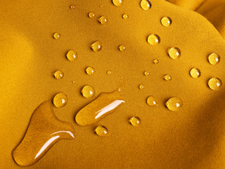 Yellow waterproof fabric with raindrops close up