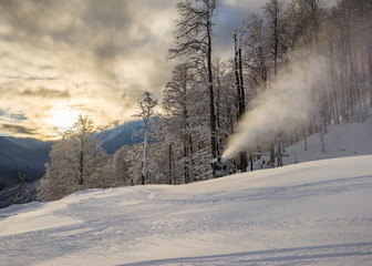 Snow gun on the ski slope on the background of beautiful landscape of the Caucasus mountains on Krasnaya Polyana at sunrise