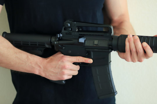 Man holding an Ar-15 assault rifle wearing black shirt