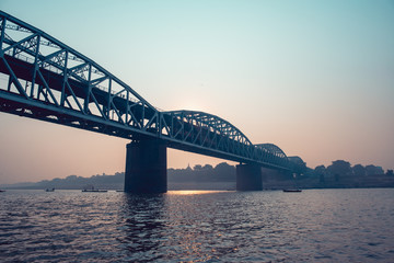 Wide angle views of a portion of the indian railway bridge of Varanasi on the holy river Ganges. View from below during a boat ride on the river at dawn.