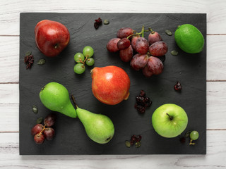 fruits background green and red color composition on dark stone slake plate and white wood table. Summer abstract creative trendy fresh health concept. Flat lay top view