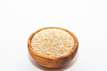 Raw quinoa in a wooden bowl isolated on white background with copy space