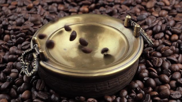 Black coffee beans slowly fall into the bowl 
