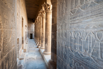 Ancient Egyptian hieroglyphs carved into a long outdoor corridor at the island Temple of Philae in...