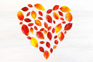 Red-yellow heart from fallen leaves on a light wooden background. A symbol of the autumn wedding,...