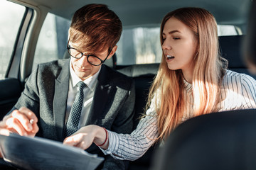 Business man and woman, business partners read documents in the car