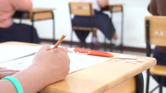 Student hand testing doing test exam with pencil drawing selected choices on answer sheet in school final exams at college or university. Taking multiple choice for assessment in examination classroom