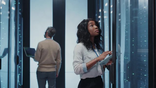 Data center coworking. Multi-ethnic couple of colleagues inspecting operational rack server cluster cloud computing at database storage cyber security.