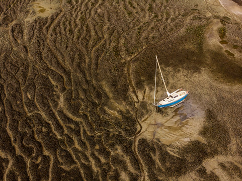 Aerial Photography From A Drone Of The Ocean Floor At Low Tide And A Beautiful Unusual Texture Of The Sea Bed From Above, On The Sandy Bottom Lies A White Sailing Yacht
