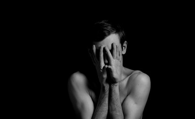 young man on a black background in a dramatic expressive pose