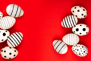 Different graphic hand-painted eggs on bright red background. Easter concept. Place for text.