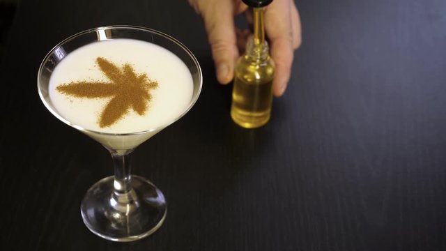 CBD oil bottle, drops of oil from a pipette in a cocktail, bar on a black background..