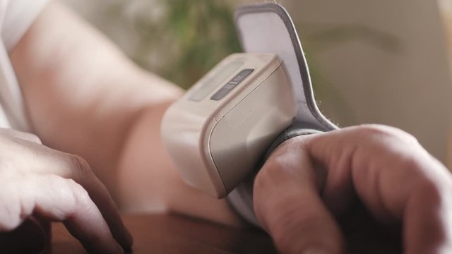 Close-up view of self measurement blood pressure using finger pressing digital sphygmomanometer. Woman health check blood pressure.and heart rate with digital pressure. Health and Medical concept.