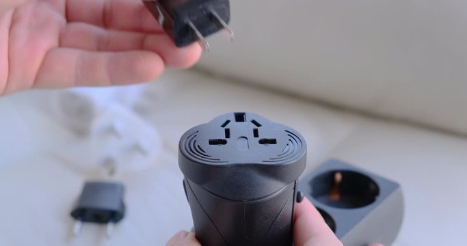 Testing electric outlet plugs (US, EU, UK) into universal travel adapter - close up.