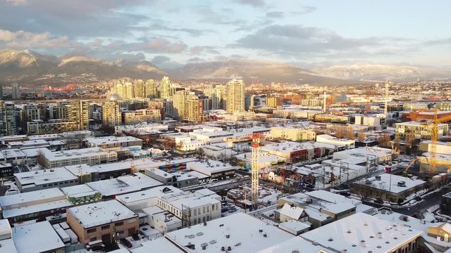 Yellow sunset light on the Vancouver Olympic village with a roofs covered with snow and several constructions going on