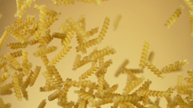 Super slow motion of flying uncooked italian pasta torti on golden background. Filmed on high speed cinema camera, 1000 fps.